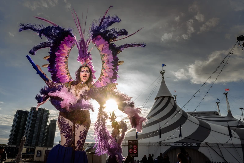 Hala performing at Cirque du Soleil Kooza in elaborate purple feathered costume with big top