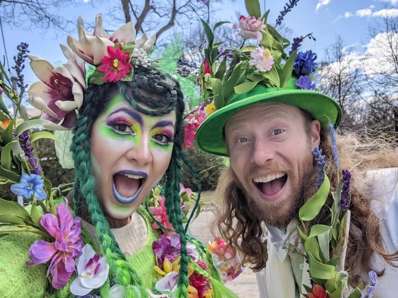 Spring garden fairy and leprechaun stilt characters in vibrant green and floral costumes