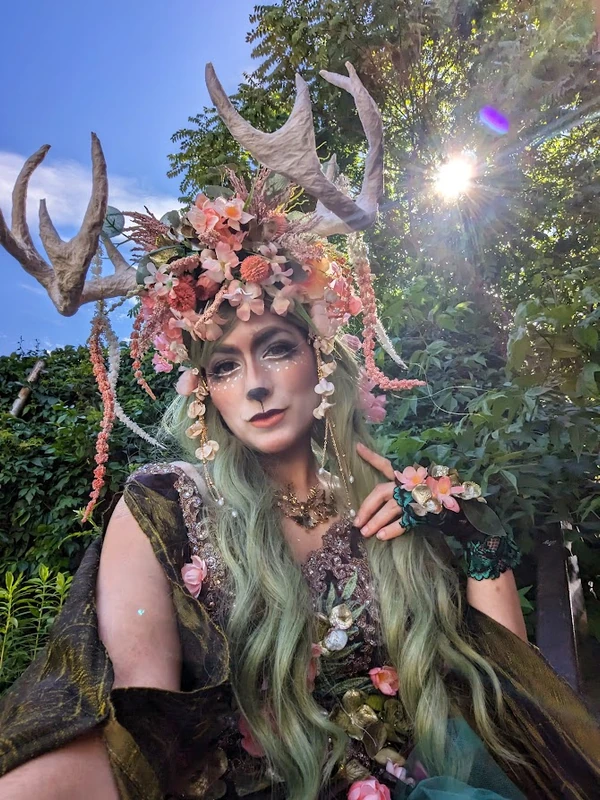 Close-up of enchanted deer forest queen stilt character with antler headpiece and floral details