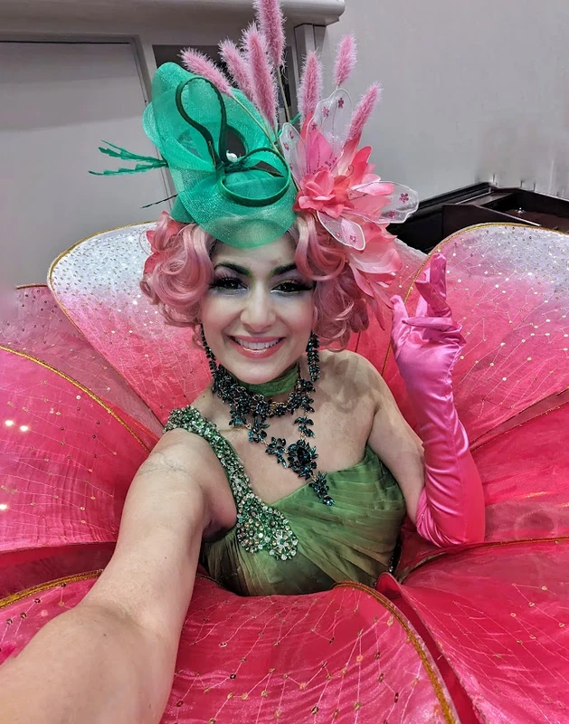 Pink flower petal stilt-walker in green and pink costume with fascinator hat