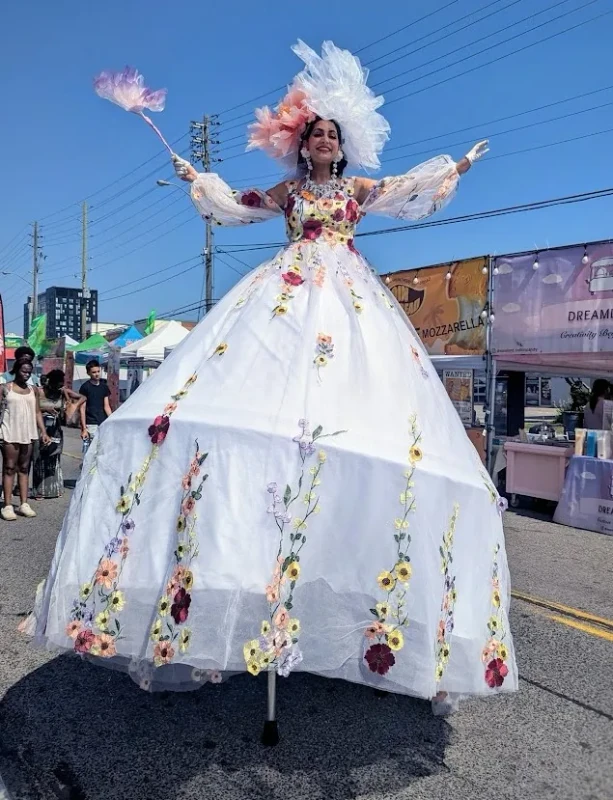 Floral garden stilt-walker in white ball gown with embroidered flowers at street festival