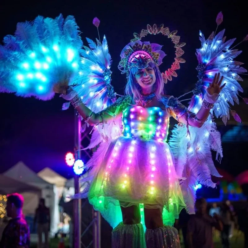 LED angel stilt-walker with rainbow-lit feather fans and illuminated dress at night festival