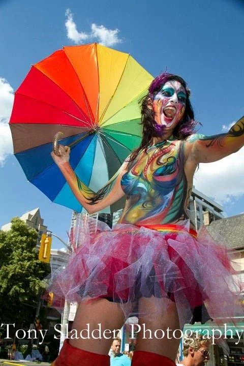 Pride stilt-walkers in rainbow costumes performing at community celebration