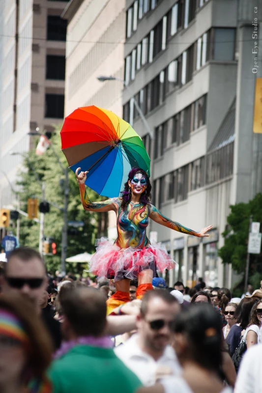 Dramatic full-length shot of Pride stilt performer in elaborate rainbow butterfly costume at sunset